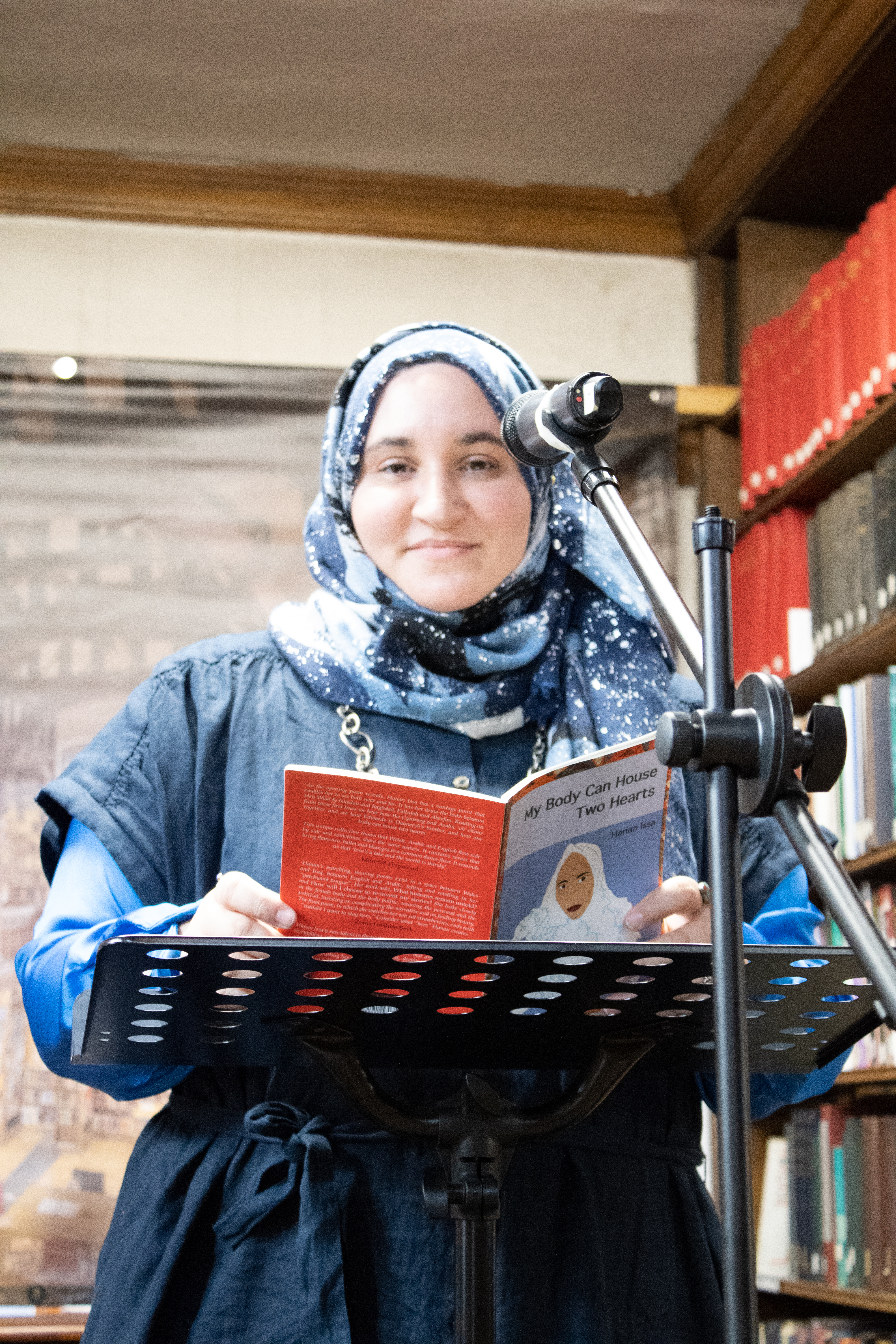 Hanan Issa, a woman in a blue headscarf, at a microphone