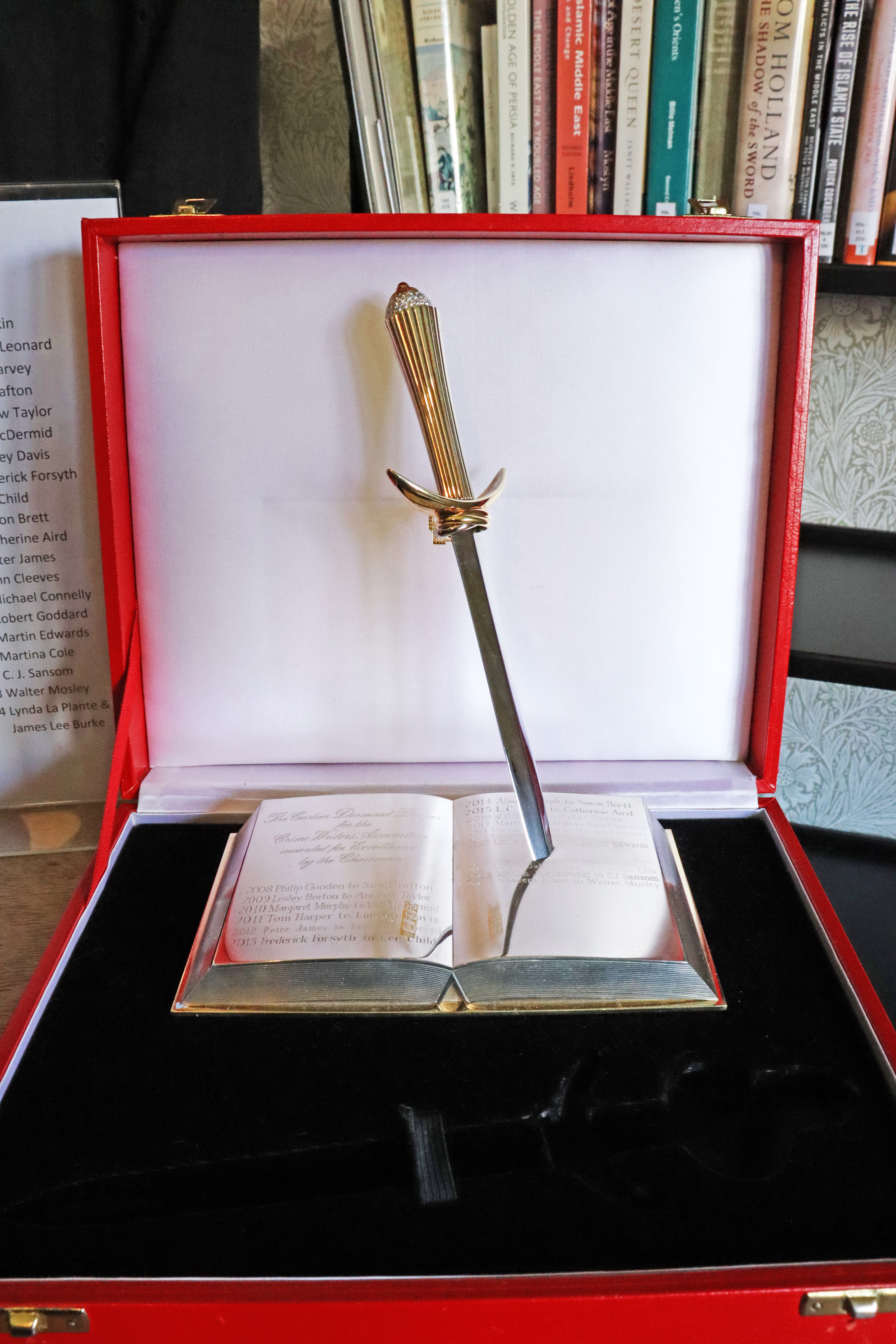 A picture of the Diamond Dagger. It's a silver sculpture (as described in the main text) sitting in on a black velvet setting and in a red box. 